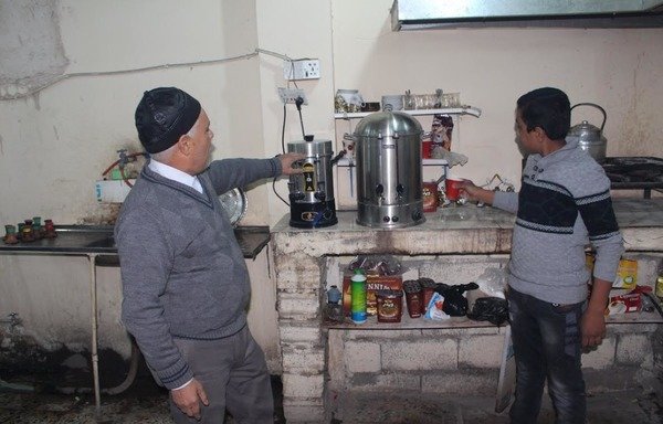 أبو رائد الحلبوسي (اليسار) صاحب مقهى سمير أميس للارجيلة في الفلوجة أعاد تأهيل محله بعد تعرضه لأضرار كبيرة خلال حكم داعش وعاد يستقبل الزبائن لشرب القهوة والشاي والارجيلة. [سيف أحمد/ديارنا]