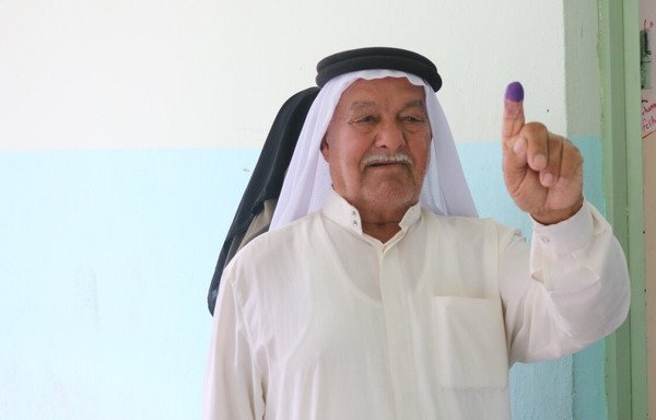الحاج خميس أبو أحمد يرفع إصبعه، وهو مغموس بالحبر الأزرق، لإظهار أنه قد صوت في محطة الاقتراع بمدرسة الجمهورية الثانوية. [سيف أحمد/ديارنا]