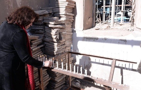 عضو في الوفد المسيحي الزائر وهو يشعل شمعة في كنيسة مار كوركيس بمحافظة الأنبار. [حقوق الصورة لمحطة الشباب الإذاعية في الرمادي]