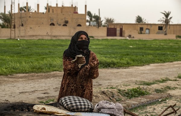 فاتن الحسن تخبز الخبز على موقد بدائي في قرية الباغوز بشرق سوريا يوم 13 آذار/مارس. [دليل سليمان/وكالة الصحافة الفرنسية]