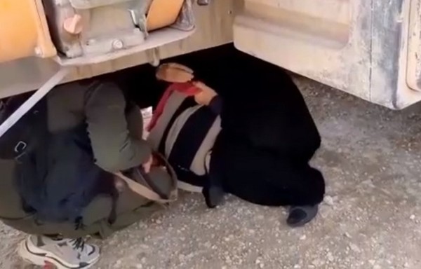 إحدى منتسبات قوات الأمن في مخيم الهول لدى محاولتها إنزال إحدى نساء داعش من أسفل الصهريج حيث يوجد مخبئ للتهريب في هذه اللقطة من شريط فيديو نشرته نورث برس.