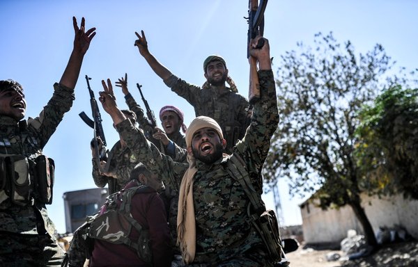 عناصر من قوات سوريا الديموقراطية المدعومة من القوات الخاصة الأميركية يحتفلون على الخطوط الأمامية في الرقة بتاريخ 16 تشرين الأول/أكتوبر 2017 بعد أن استعادوا المدينة من قبضة داعش. [بولنت كيليتش/وكالة الصحافة الفرنسية]
